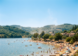 Canicule en Bourgogne : où se baigner en toute sécurité cet été ? Crowded lakeside beach with swimmers, sunbathers, umbrellas, and small boats near forested hills
