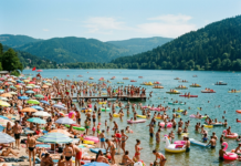 Canicule en Alsace : où se baigner en toute sécurité cet été ? Crowded lakeside beach with numerous people sunbathing, swimming, and using inflatable floats