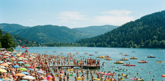 Canicule en Alsace : où se baigner en toute sécurité cet été ? Crowded lakeside beach with numerous people sunbathing, swimming, and using inflatable floats